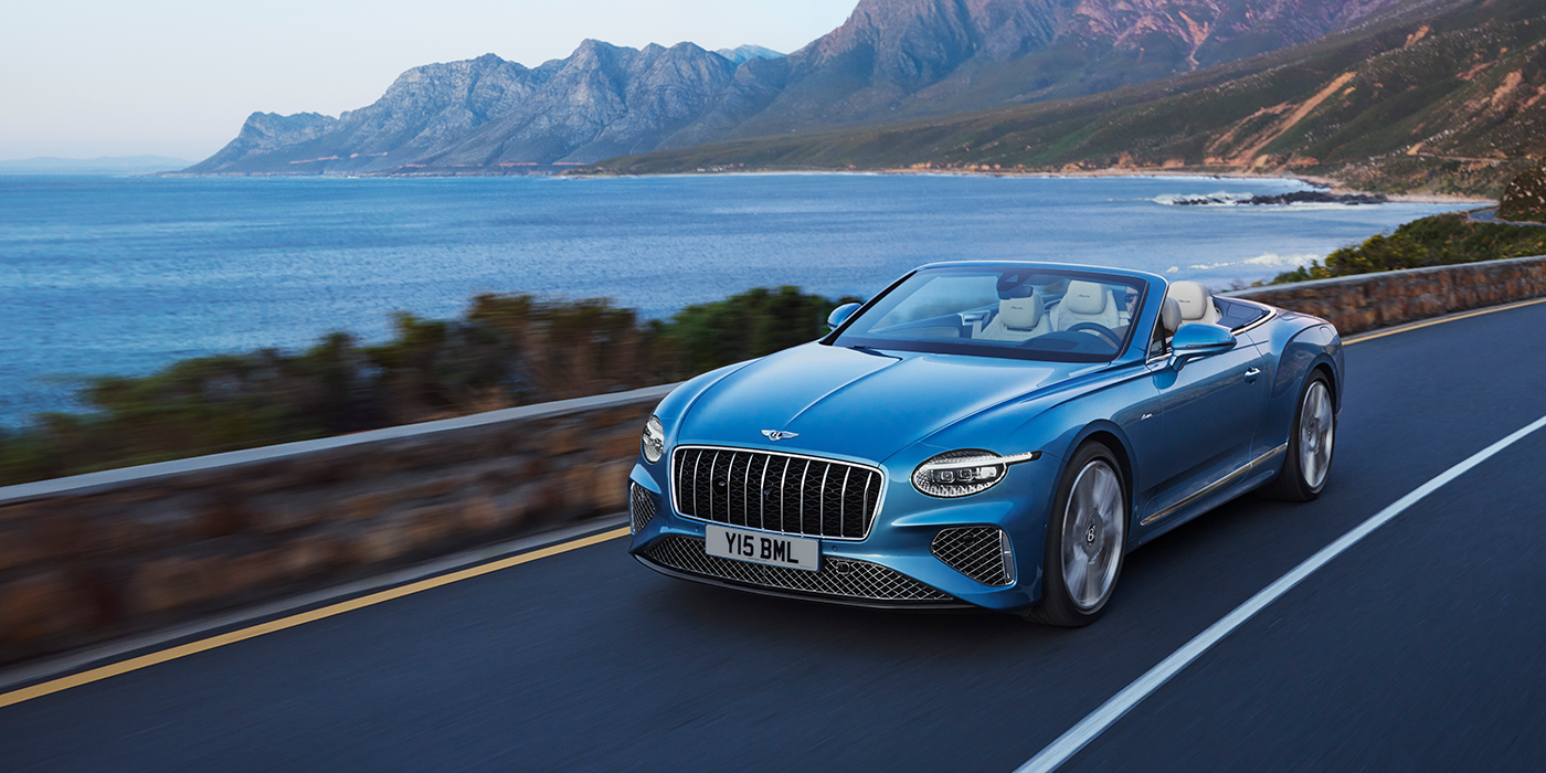 Bentley Copenhagen New Bentley Continental GTC Azure convertible in Light Windsor blue paint with 22 inch Azure wheels and chrome grill, driving dynamically by the sea