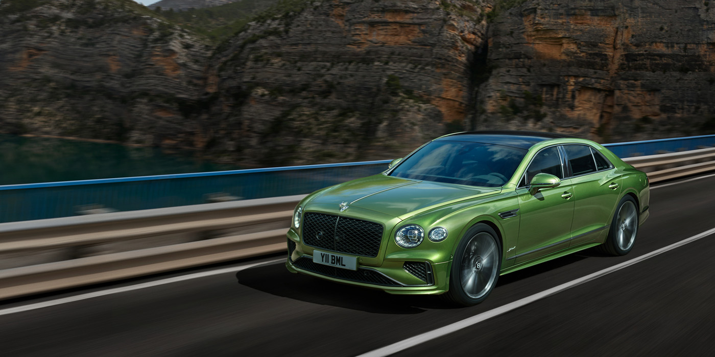 Bentley Copenhagen Bentley New Flying Spur Speed v8 hybrid sedan driving dynamically on a mountain road in Tourmaline Green paint