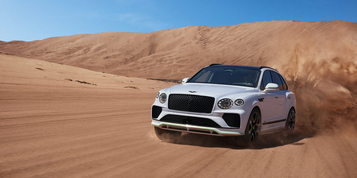 Bentley Copenhagen Bentley Bentayga Speed SUV front three quarter in Snow Quarts Pearlescent by Mulliner white paint driving dynamically through the desert