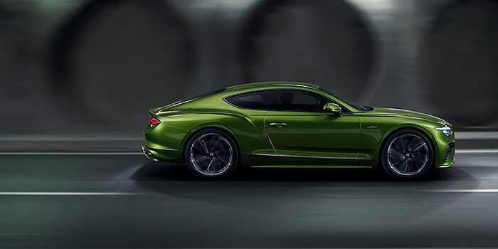  Bentley Copenhagen Bentley Continental GT coupe in Tourmaline Green paint driving in profile on a dark road