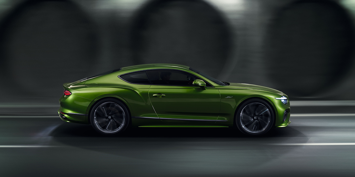 Bentley Copenhagen Bentley Continental GT coupe in Tourmaline Green paint driving in profile on a dark road