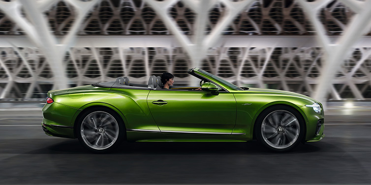 Bentley Copenhagen Bentley Continental GTC Speed convertible side profile in Tourmaline Green paint driving dynamically on a bridge at night