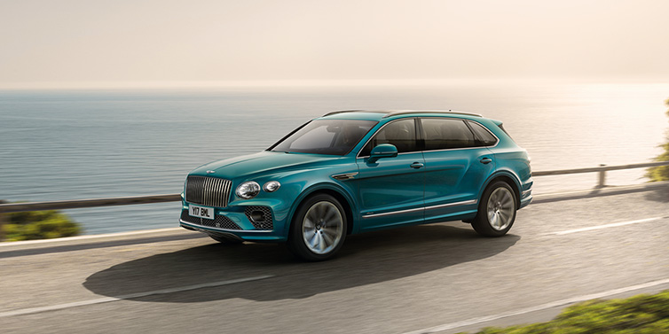 Bentley Copenhagen Bentley Bentayga Extended Wheelbase Azure SUV in Topaz blue paint driving dynamically by the ocean