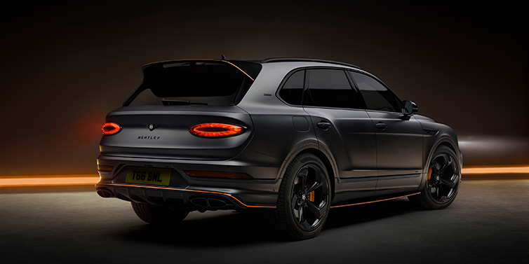 Bentley Copenhagen Bentley Bentayga S Black Edition SUV rear three quarter in Anthracite Satin paint against a dark red and yellow background