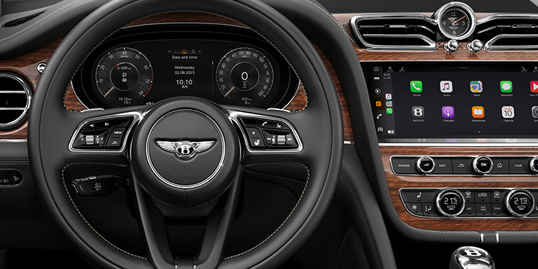 Bentley Copenhagen Bentley Bentayga SUV front interior detail of steering wheel and driver screens surrounded by Beluga black hide and Crown Cut Walnut veneer