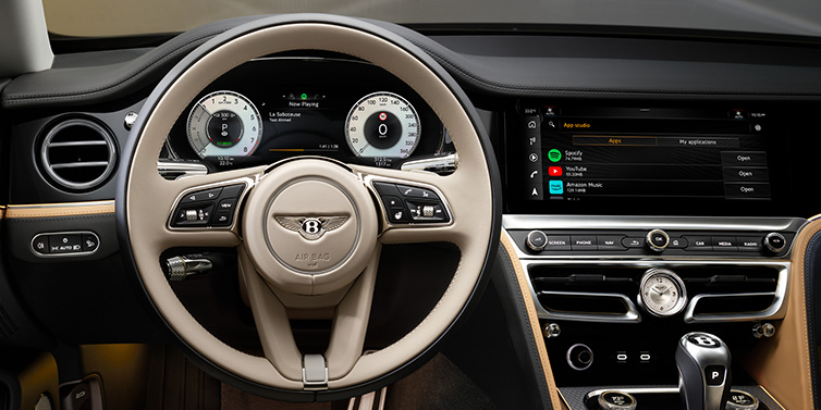 Bentley Copenhagen Bentley Flying Spur Mulliner sedan front interior detail of steering wheel and driver screens surrounded by Linen and Beluga black hides