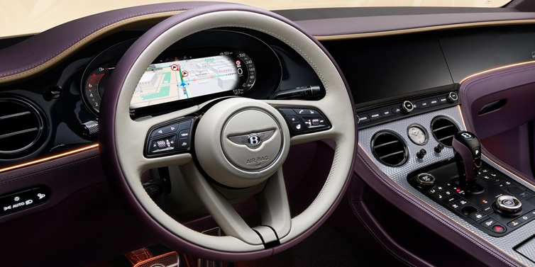 Bentley Copenhagen Bentley Continental GT Mulliner coupe front interior showing steering wheel and drivers screens surrounded by Linen and Damson hides and Grand Black veneer