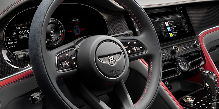 Bentley Copenhagen Bentley Flying Spur Speed sedan front interior detail showing steering wheel and driver screens surrounded with Hotspur red and Gravity Grey hides